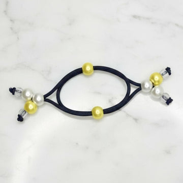 Black hair tie with yellow and white beads on a marble background