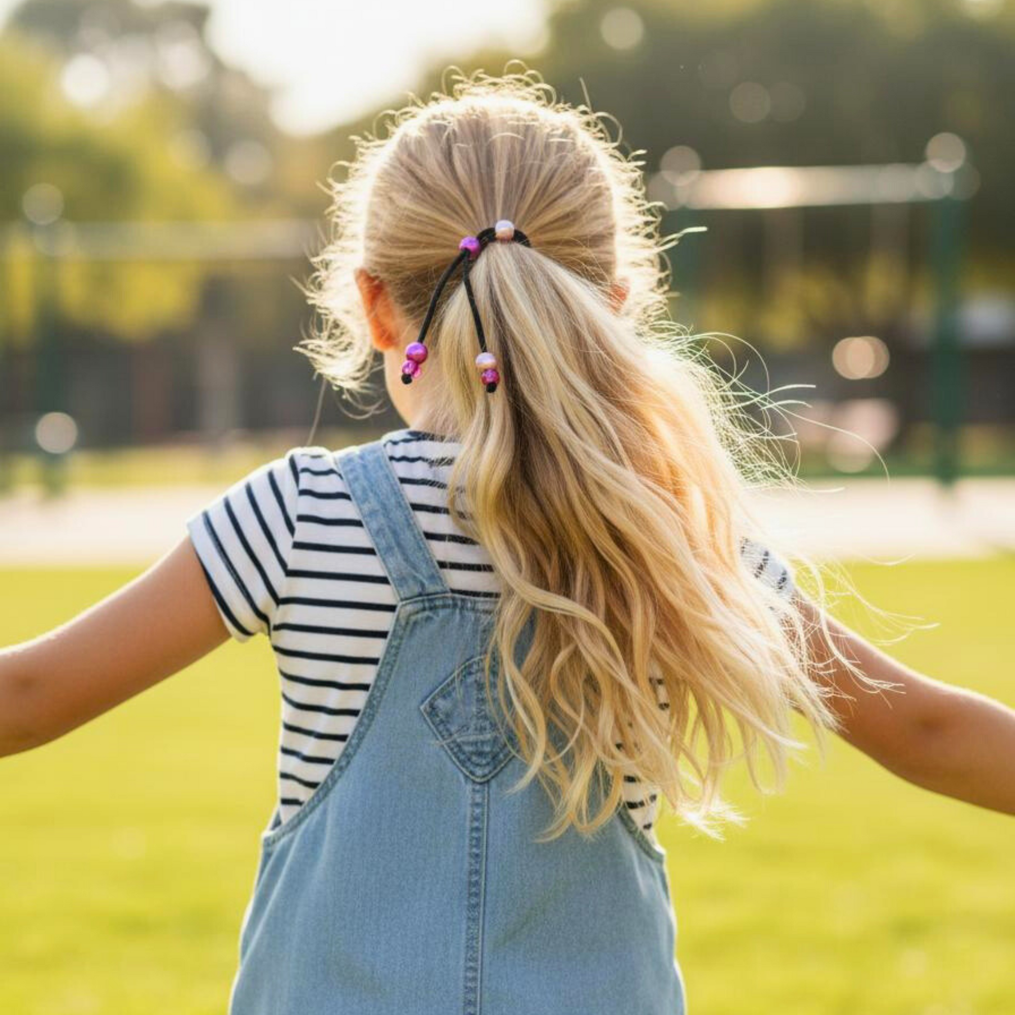 Young child wearing PonyPop™ QuickPop™ - Blush Pink hair tie while running
