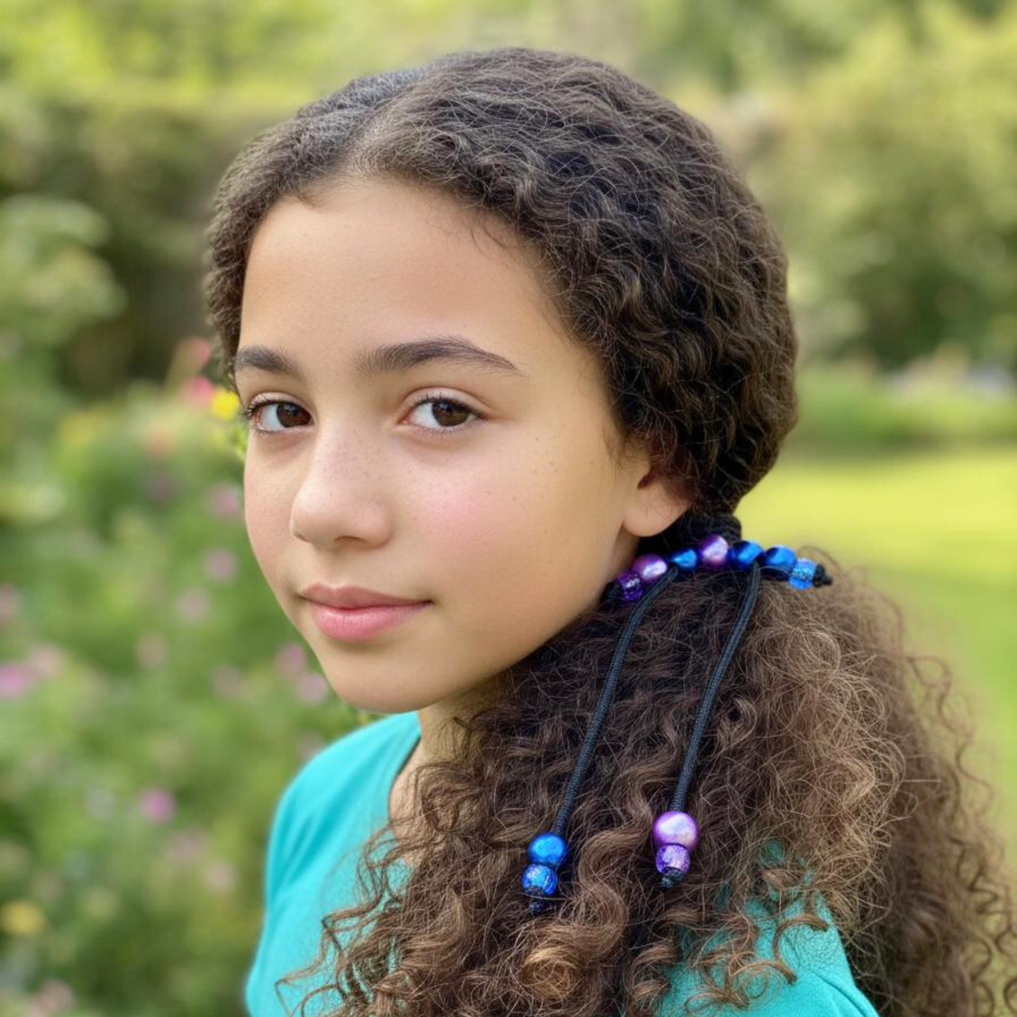 Young girl with braided hair wearing colorful beads outdoors