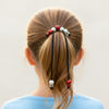 Person with a ponytail using hair ties with beads on a plain background