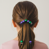 Person with a ponytail decorated with colorful beads against a plain background