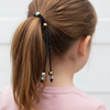Person with a ponytail using a hair tie with beads on a plain background