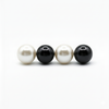 Two white pearls and two black pearls on a white background