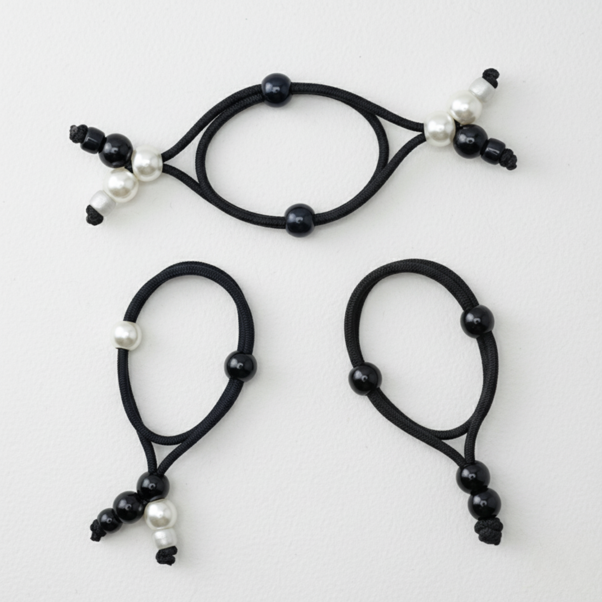 Set of three black hair ties with pearls on a white background