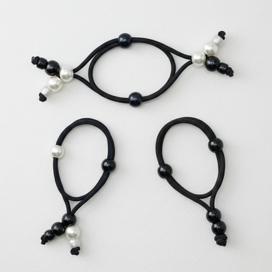 Set of three black hair ties with pearls on a white background