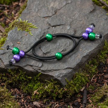 Black hair tie with green and purple beads on a green background