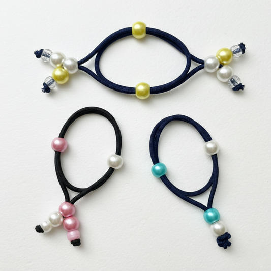 Three black hair ties with colorful beads on a white background
