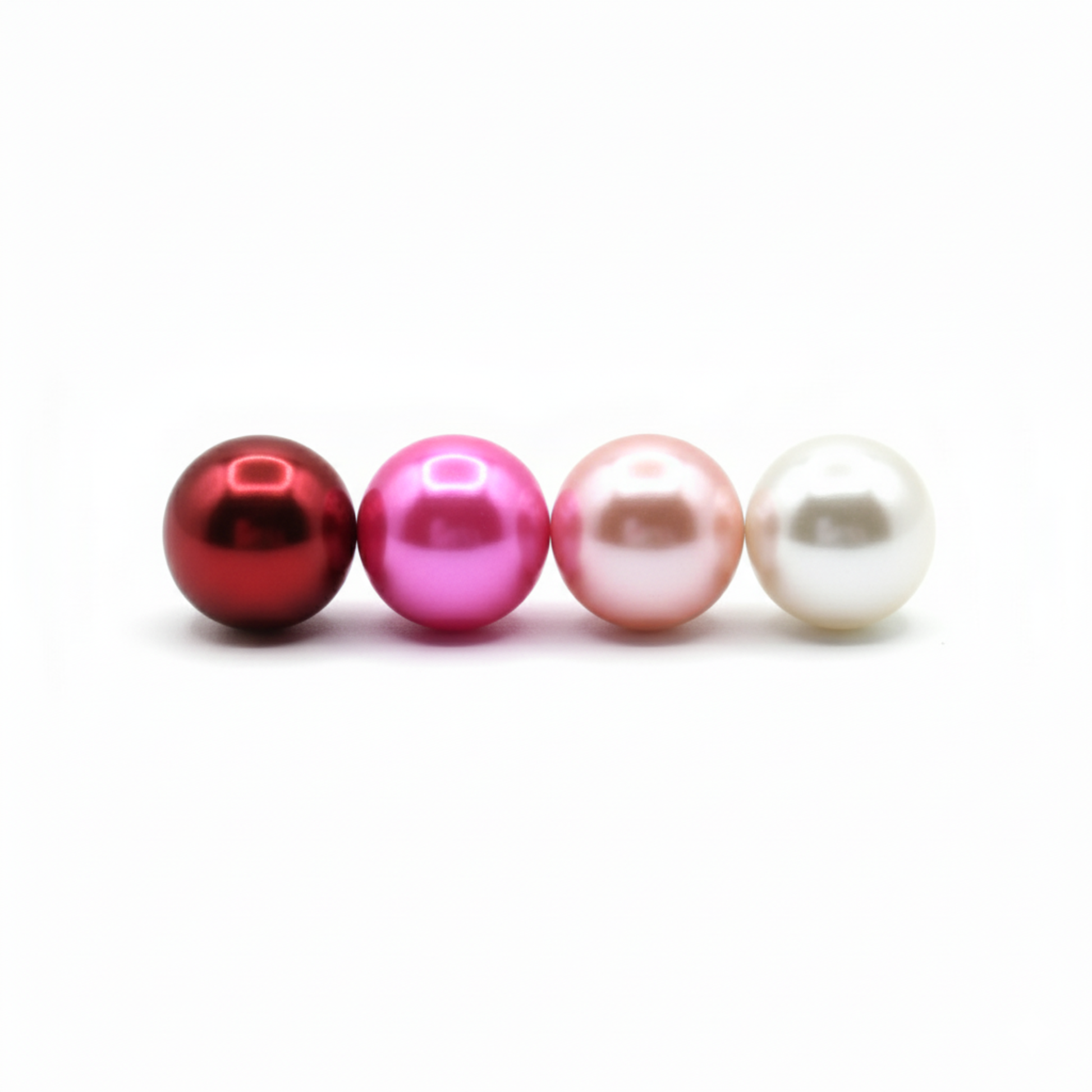 Four pearls of different colors arranged in a row on a white background