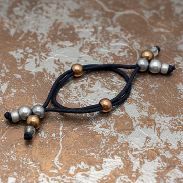 Navy blue hair tie with gold, silver, and black beads on a gray background