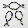 Three navy blue hair ties with gold and silver beads on a white background