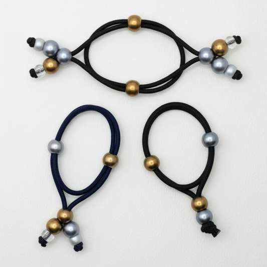 Three navy blue hair ties with gold and silver beads on a white background