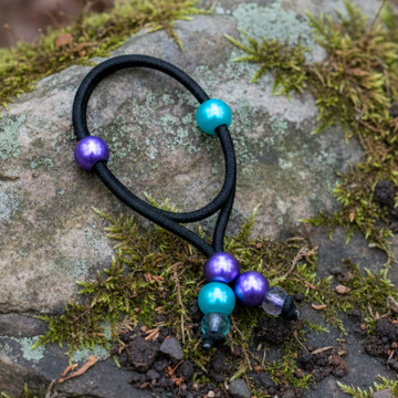 Black hair tie with colorful beads on a green background