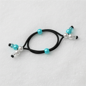 Black hair tie with turquoise and pearl beads on a light blue background