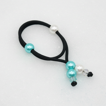 Black hair tie with turquoise and white beads on a light blue background
