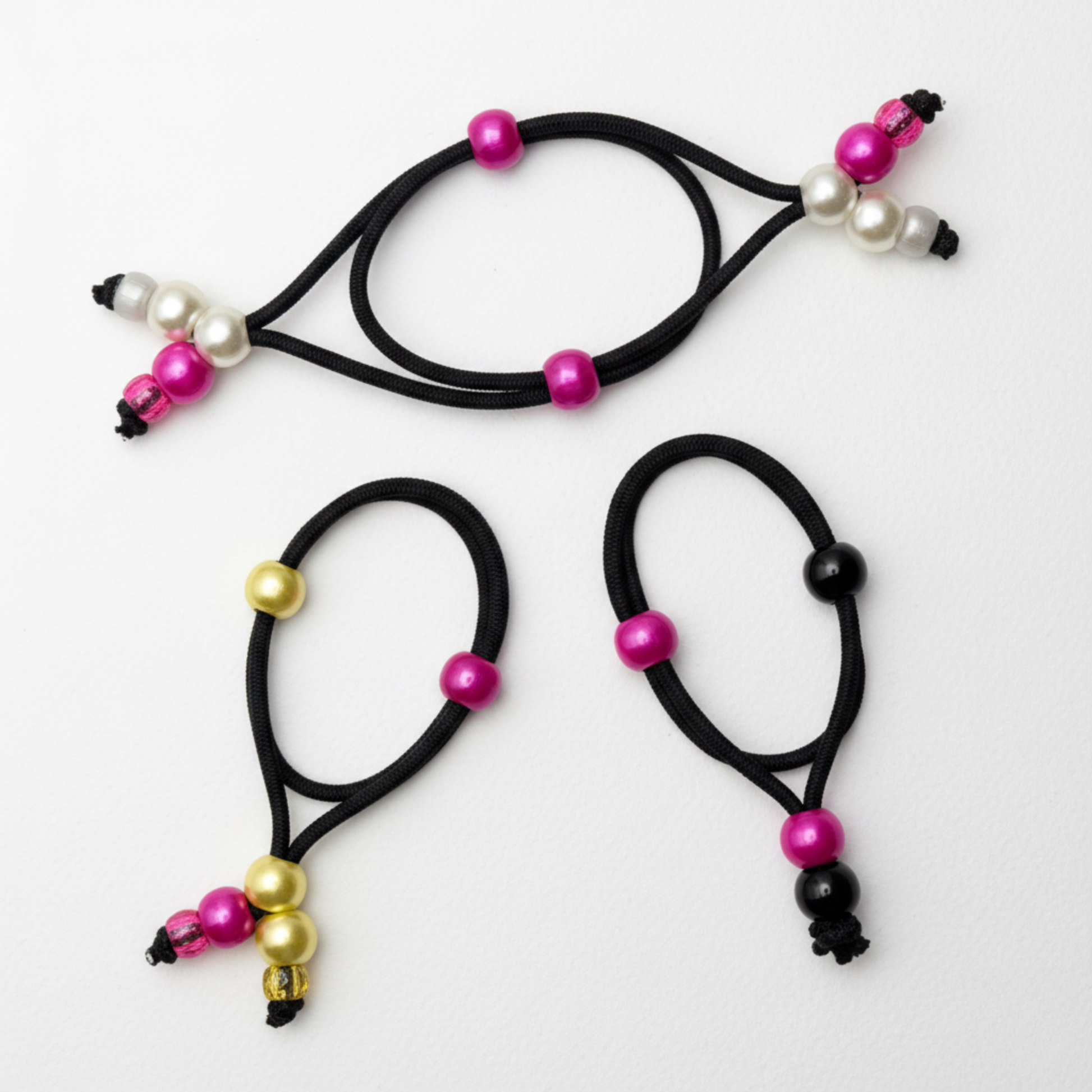 Three black hair ties with colorful beads on a light gray background