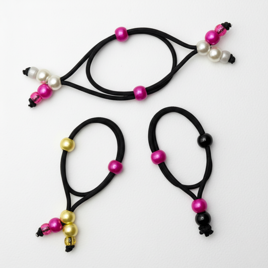 Three black hair ties with colorful beads on a light gray background