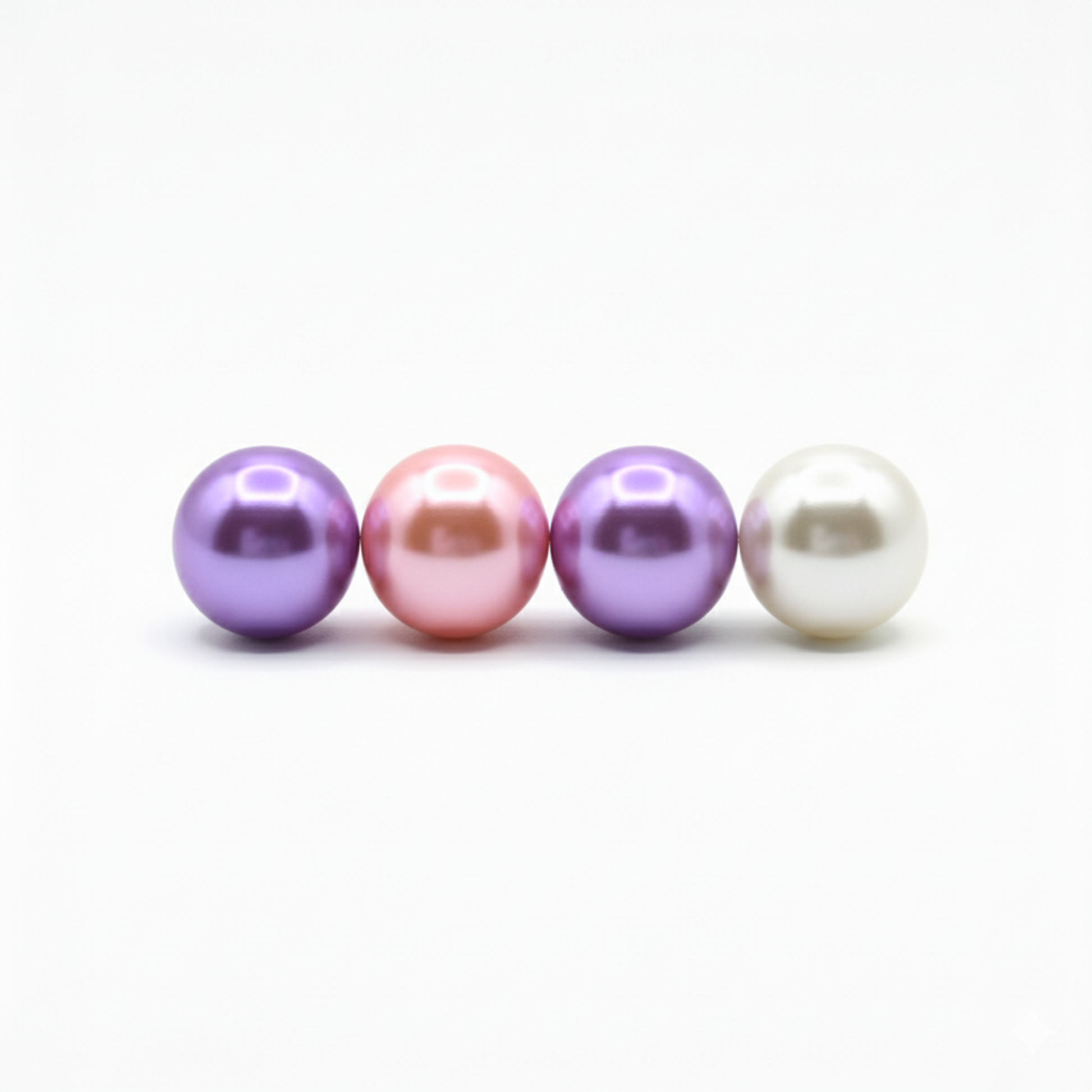 Four pearls of different colors arranged in a row on a white background