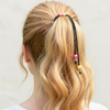 Person with blonde hair tied back using a colorful hair tie against a plain background