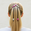 Person with a ponytail using decorative hair ties on a plain background