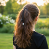 Person with long hair in a ponytail standing in a park at sunset.