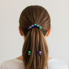 Person with a ponytail featuring colorful beads against a plain background