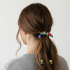 Person with a colorful beaded hair tie in a ponytail against a plain background