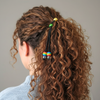 Person with curly hair tied back with a colorful hair tie against a neutral background