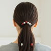 Person with a ponytail featuring decorative hair ties on a plain background