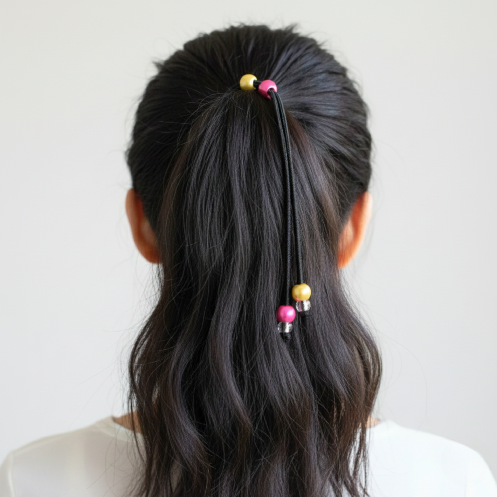 Person with long black hair tied back with colorful hair ties against a white background