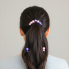 Person with a ponytail wearing colorful hair ties against a neutral background