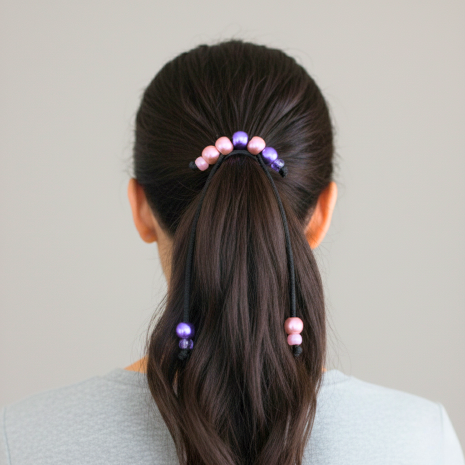 Person with a ponytail wearing colorful hair ties against a neutral background