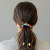 Person with a ponytail featuring colorful hair ties against a neutral background