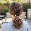 Person with a ponytail featuring a rainbow hair tie outdoors