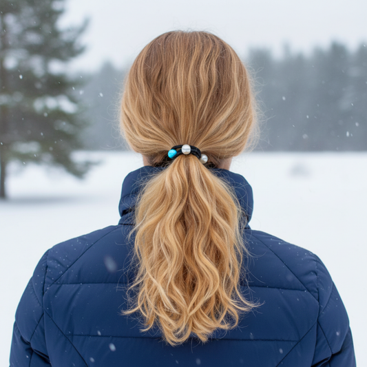 Person with a ponytail wearing a blue jacket in a snowy landscape