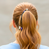 Person with styled hair featuring a hair tie and beads against a neutral background